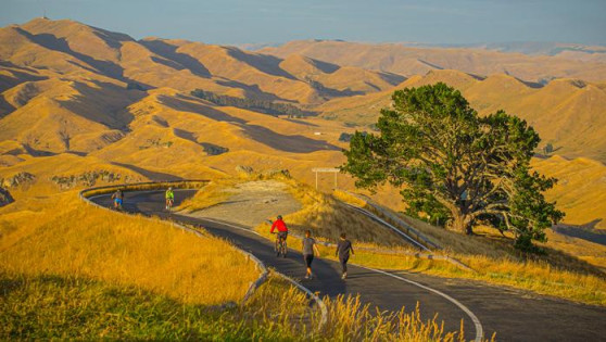 hills in the background with people walking and cycling up a road