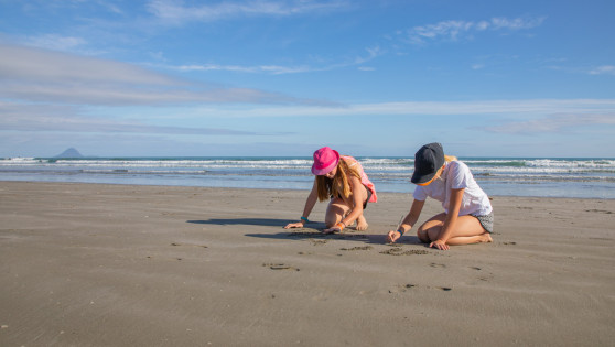 Two kids playing in the sand on a beach.